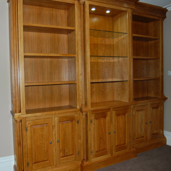 traditional bespoke solid oak unit with both solid oak and glass shelves with recessed lighting and swan hinges in a clear lacquer finish